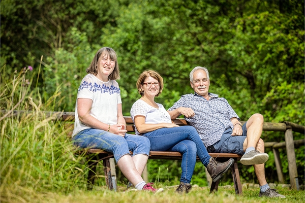 Drei Menschen sitzen auf einer Bank im Grünen. Drei Menschen sitzen auf einer Bank im Grünen.