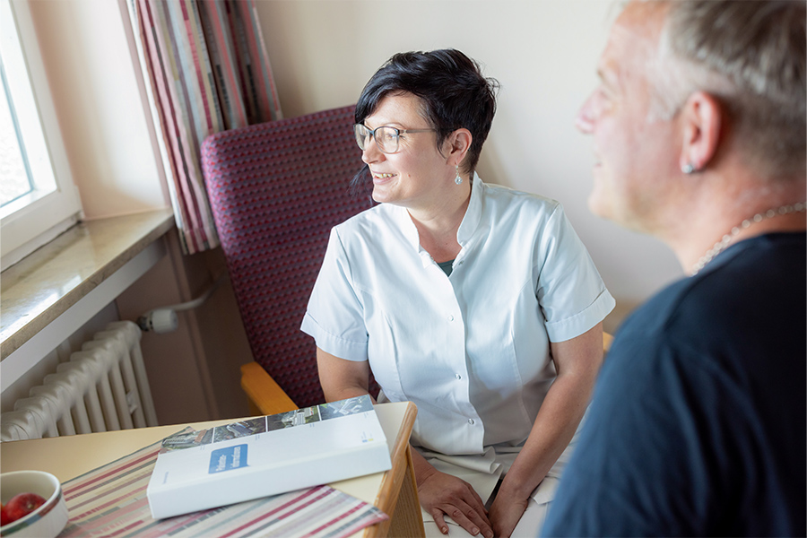 Eine Pflegerin und ein Patient sehen gemeinsam aus dem Fenster.