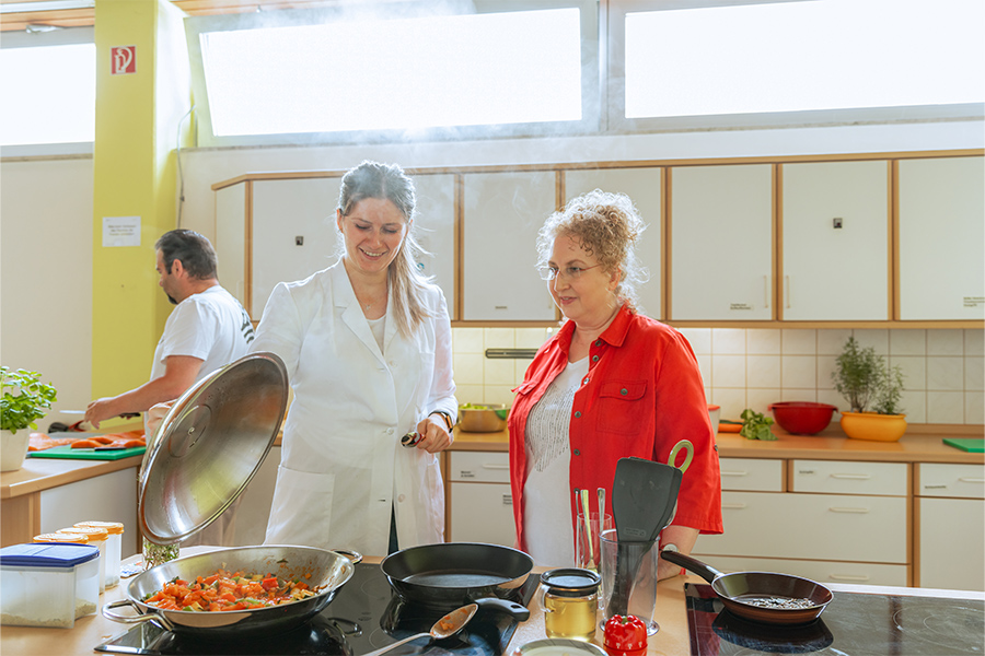 Eine Patientin lernt in der Lehrküche eine Gemüsepfanne zu kochen.