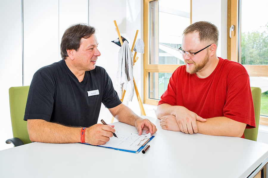 Ein Therapeut und ein Patient sitzen sich gegenüber und besprechen den Therapiefortschritt.