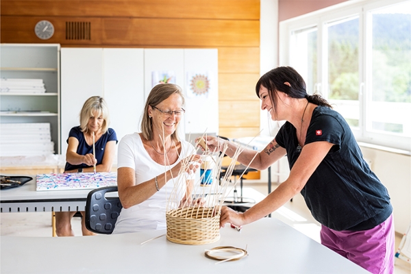 Eine Therapeutin hilft einer Patientin beim Flechten eines Korbes. Eine Therapeutin hilft einer Patientin beim Flechten eines Korbes.