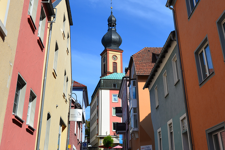 Eine Straße in Bad Brückenau und der Kirchturm von St. Bartholomäus.