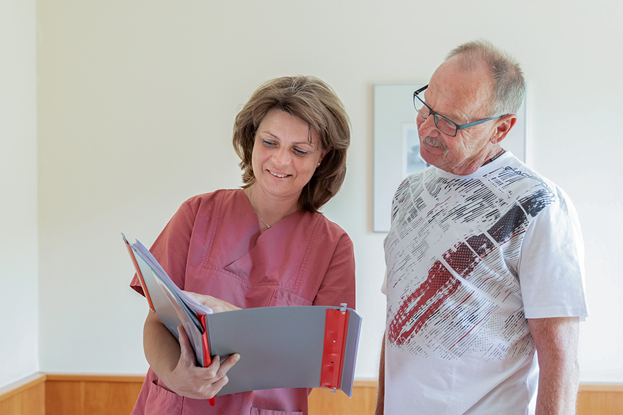Eine Pflegerin und ein Patient schauen gemeinsam in dessen Patientenakte.